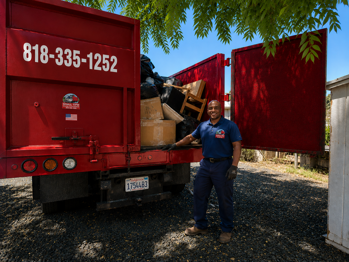 Small Time Hauling crew member at the rear of a fully loaded dump truck with tailgate open
