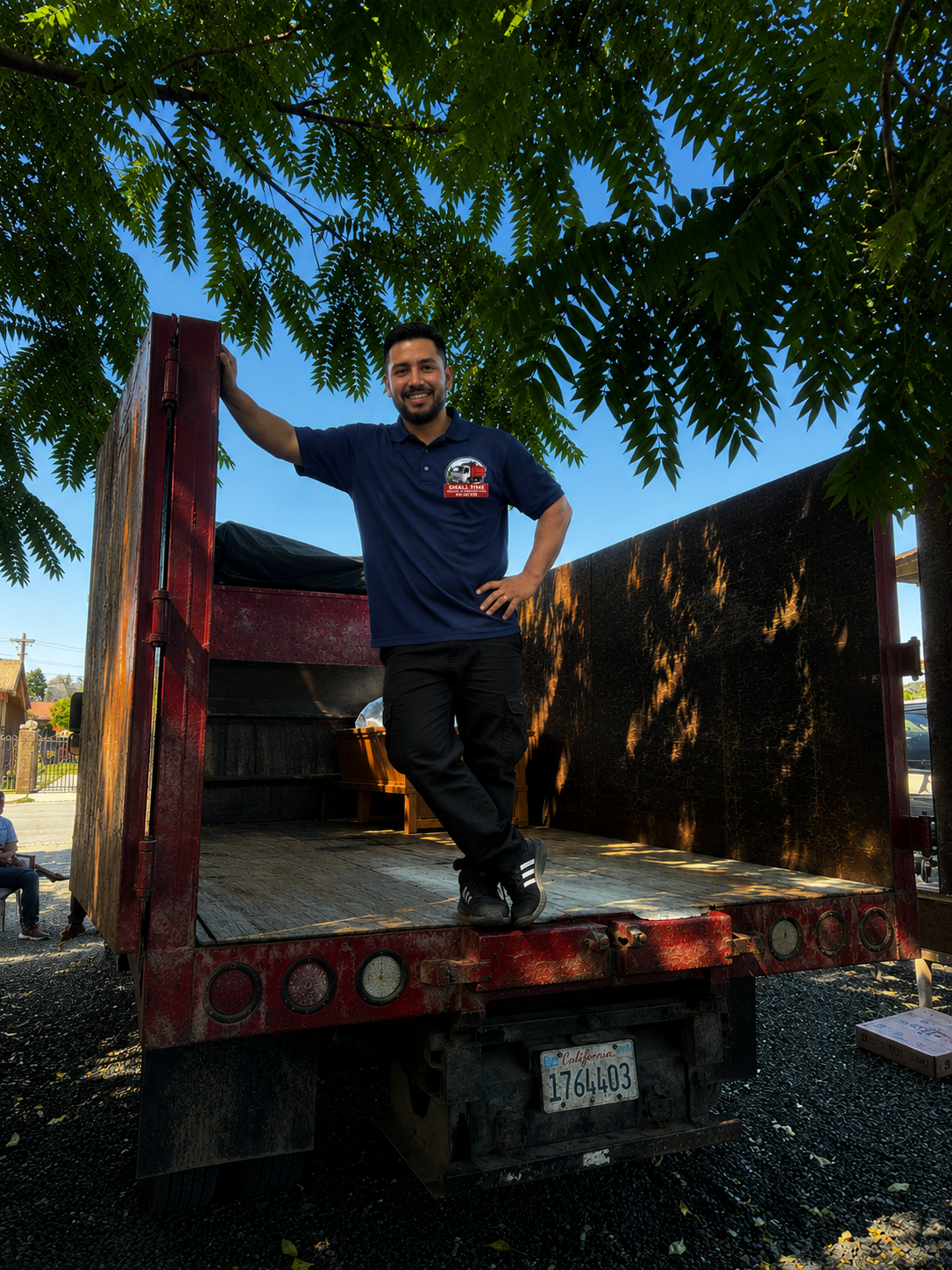 Small Time Hauling owner standing inside the dump truck bed under a shady tree